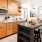 Spacious and well lit kitchen with wood floors and stainless steel appliances. 