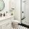 Large well lit bathroom with large mirror and white cabinets with a spacious walk in closet.
